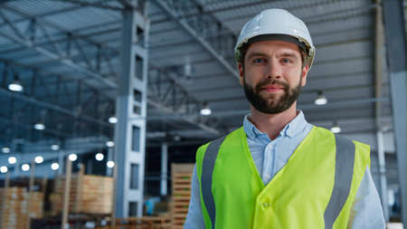Portrait warehouse specialist smiling camera enjoying work holding tablet. Professional caucasian...