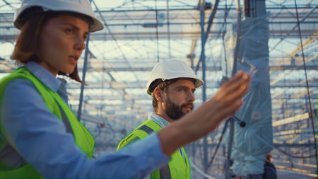 Portrait manufacture workers talking about production plan inspecting greenhouse. Professional...