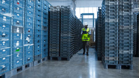 Uniformed storehouse employee checking factory product shipment boxes counting. Professional storage...