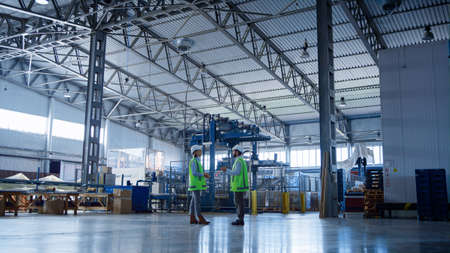 Factory storage employees talking about storehouse delivery boxes inspecting. Professional...