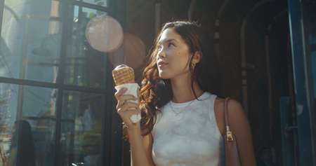 Smiling asian woman enjoying ice cream outdoors on summer weekend closeup. Glamour brunette lady...