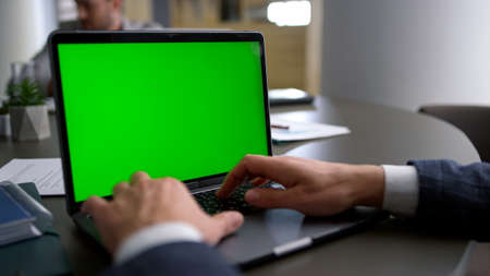 Manager typing laptop keyboard green screen analyze corporate data in office conference table. Close up executive man hands using computer on business meeting with colleagues. Technology busy concept.の写真素材