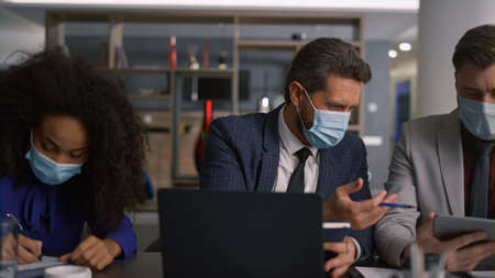 Multi ethnic financial employees group working together wearing protective face mask on conference....