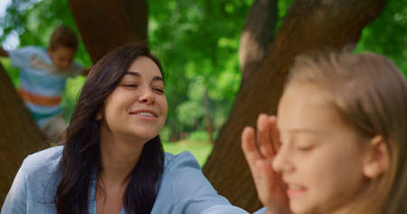 Smiling mother caress daughter on picnic summerday close up. Brunette woman touching girl face...