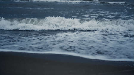 Waves foam splashing beach in sea background landscape. Blue ocean storming sand coast line close...