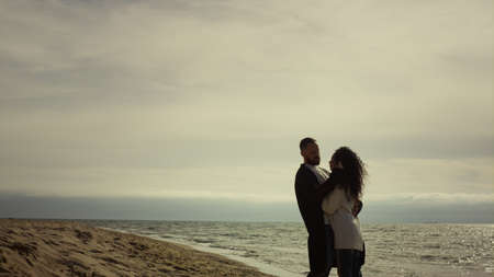 Couple standing sea beach in casual clothes Beautiful lovers hugging at seaside. Calm people looking...