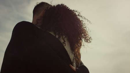 Two lovers enjoy hugging on sunny day outdoors. Ethnic couple embracing at sunset close up. Unknown...