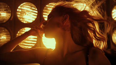 Hot woman seducing by dancing sexually in night club lights close up. Sensual allure lady moving...