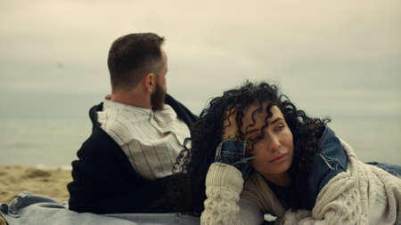 Beautiful couple rest together on beach. Mixed race people enjoy vacation at ocean coast. Calm boyfriend girlfriend lying on shore. Close up two lovers chilling out on romantic picnic. Love concept.の写真素材