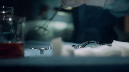 Closeup surgeon operating hands in ward. Unknown nurse give medical instruments. Doctors team working performing surgery in intensive care unit. Healthcare workers provide surgical treatment in clinicの写真素材