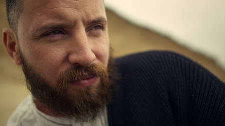 Thoughtful man face looking away on nature background. Handsome caucasian bearded guy adult thinking...