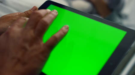 Man holding tablet computer with chroma key screen in clinic room close up. Unrecognized doctor hand...