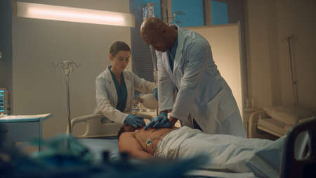 Doctor performing cpr in emergency unit room. Nurse assisting with oxygen mask. Confident african...