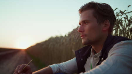 Portrait handsome farmer looking in camera. Confident agrarian rest at sunset. Smiling man...