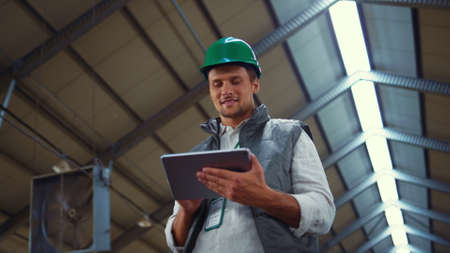Agribusiness worker using tablet computer in shed. Dairy production engineer. Handsome smiling man...