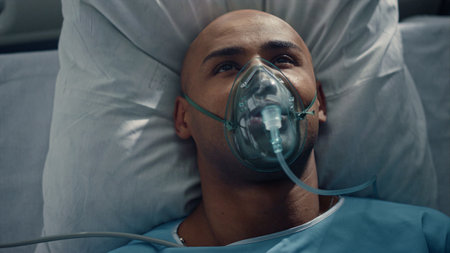 Portrait patient breathing oxygen mask lying in bed hospital emergency unit. Tired african american...