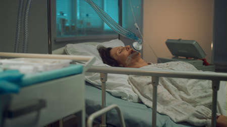 Sick woman oxygen mask lying in hospital bed. Terminally ill person in clinic. Unconscious woman...