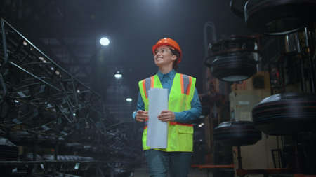 Cheerful woman supervisor walking at digital manufacturing company warehouse. Industrial brunette...