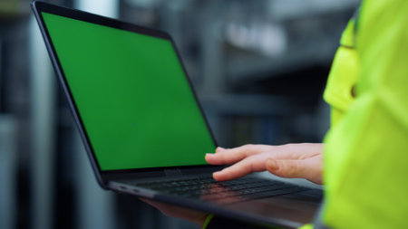 Unrecognizable woman typing laptop computer greenscreen on factory. Closeup supervisor hands using touchpad looking chroma key screen in industrial plant. Modern digital project work concept.の写真素材