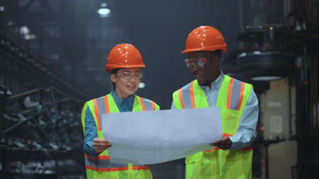 Professional partners holding paper plan manufacturing company project. Attractive man supervisor...
