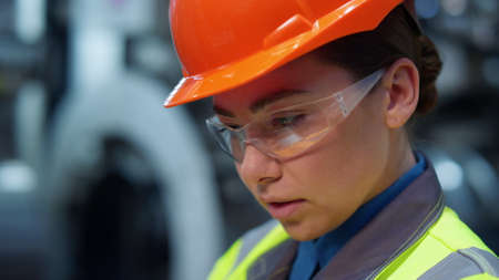 Professional engineer looking camera wearing safety uniform in modern facility. Uniformed...