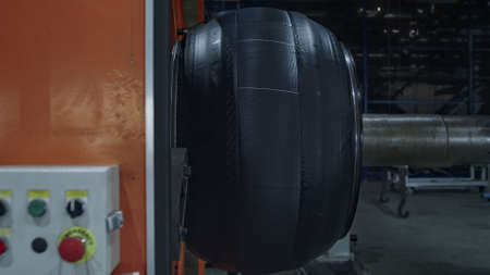 Automobile tire production machine working process at technological factory. Modern industrial orange automat with buttons manufacturing rubber car tyre in manufacture. Producing automation conceptの写真素材