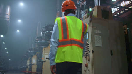 Man professional supervisor analysing huge metal construction work at storage. Black hair calm...