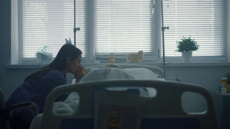 Upset woman visiting sick child after therapy. Hospital operating ward interior. Worried mother...