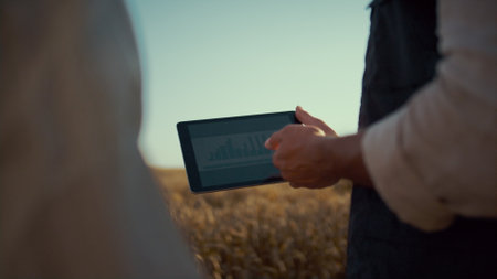 Farmer hands holding pad computer closeup. Agribusiness team checking diagram. Unrecognized...