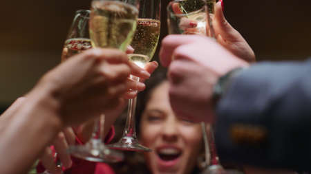Beautiful woman drinking alcohol with friends group on restaurant celebration. Close up people hands clinking drink glasses in bar. African american girl enjoy friends meeting in cafe. Party concept.の写真素材