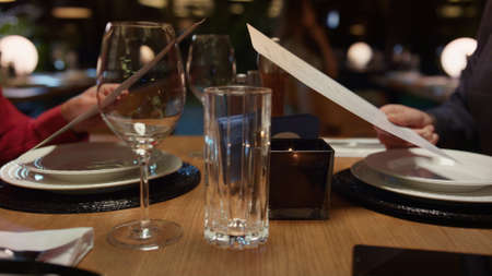 Couple hands choosing menu food in luxury italian restaurant. Two mixed race people looking deciding...