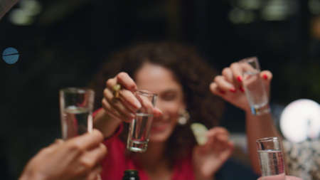 African american woman having fun with close friends. Closeup young people hands clink drink glasses in stylish bar. Friends group drinking alcohol at new year party celebration. Enjoy leisure conceptの写真素材