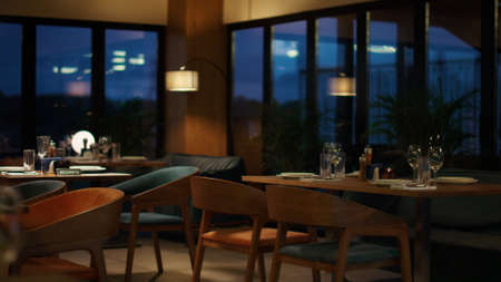 Alone woman sitting at restaurant in evening big city. Beautiful lady waiting date in luxury cafe. Modern cutlery set on cafeteria table in cozy design hotel lounge. Going out dining food concept.の写真素材