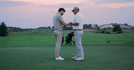 Angry golf players sign document contract at green course. Sport team argue at country club. Two...