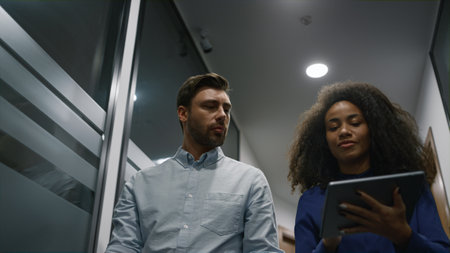Multiracial entrepreneur couple working tablet device discuss business start up in office hallway....