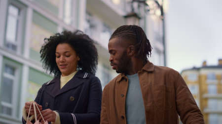 Cheerful lovers walking city street together portrait. Adorable smiling couple. Attractive african...