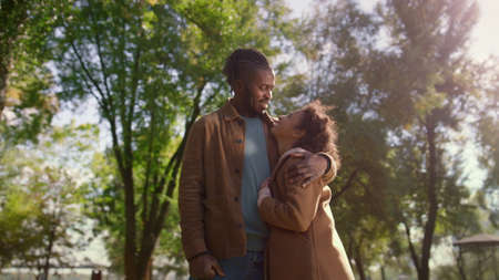 Portrait loving father hugging smiling daughter looking each other green park. Smiling african...