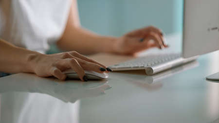 Businesswoman hands working desktop computer at futuristic office close up. Unrecognized project manager freelancer holding mouse typing wireless keyboard at workplace. Woman surfing collecting dataの写真素材
