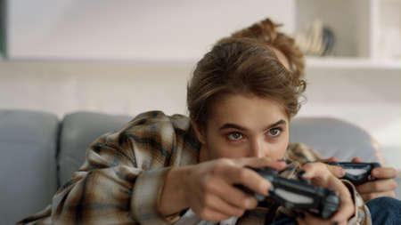 Playful couple enjoy joysticks game at home closeup. Excited players having fun. Beautiful competitive wife happy ginger husband playing online shooter cheating. Gamers tournament on weekend evening.の写真素材