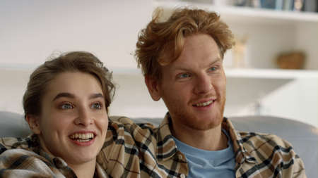 Happy family watch comedy movie have good time in living room together closeup. Redhead man pretty...