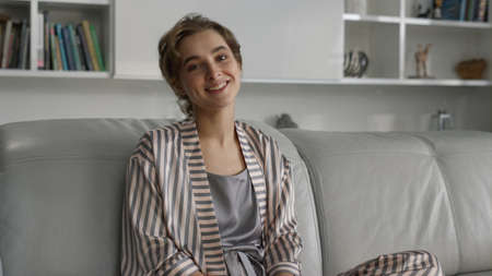 Attractive lady resting living room closeup. Relaxed girl posing in pajamas enjoying morning at cozy home. Smiling freelancer taking break chilling on sofa after work. Tired mother dream think aloneの写真素材