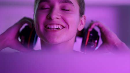 Esport girl looking computer screen closeup. Happy winner take off headphones. Beautiful smiling...
