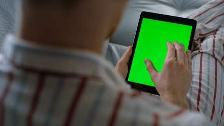 Businessman swiping mockup tablet at home closeup. Green screen template device. Unknown businessman...
