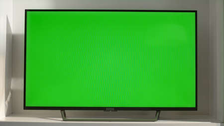 Chroma key smart TV in living room closeup. Device with blank screen in sunlight. Flat screen TV set...