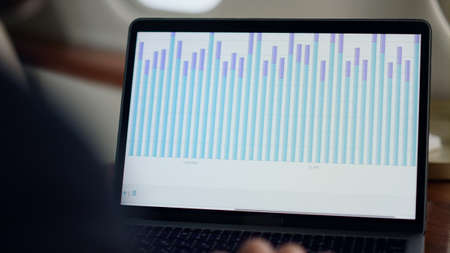 Closeup laptop finance chart on airplane. Business analyst hands typing computer analyzing sales...