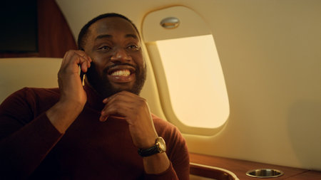 Joyful man calling friend in airplane closeup. Happy african american discussing deal. Happy...
