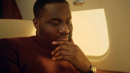 Guy using mobile phone in private jet closeup. Smiling bearded man hold in hands cellphone on...
