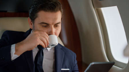 Handsome businessman looking tablet at window. Closeup man working on business trip. Focused stylish...