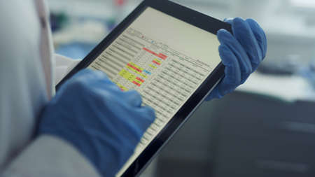 Doctor hands using tablet checking health history data in clinic office close up. Unknown physician magnifying image tables watching vaccination results on pad screen. Modern technologies in hospital.の写真素材