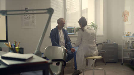 Professional medic putting cuff measuring blood pressure on senior patient arm. Elderly man visit therapist in modern hospital. Woman doctor examining pensioner health in clinic. Healthcare concept.の写真素材